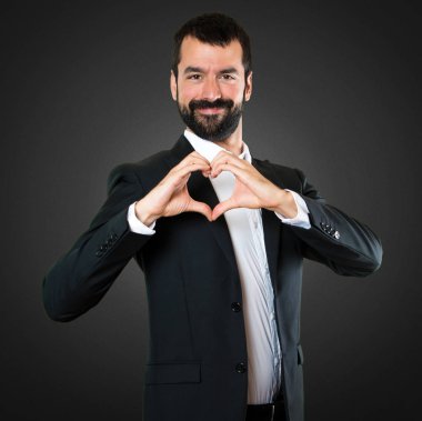 Yakışıklı işadamı siyah sırt üstü elleri ile bir kalp yapma