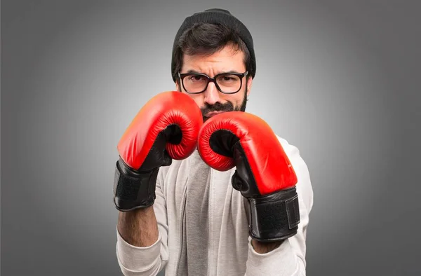 Uomo hipster con guantoni da boxe su sfondo grigio — Foto Stock