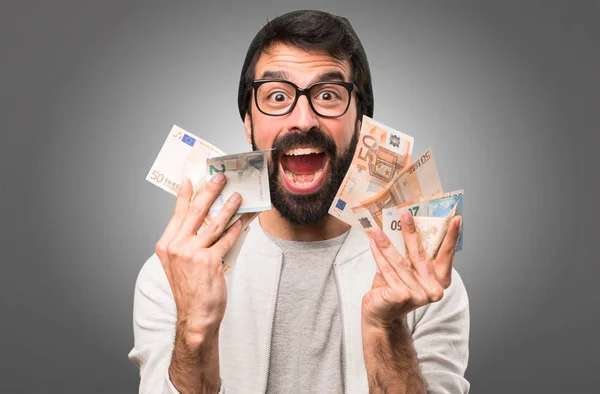 Feliz Hipster hombre tomando un montón de dinero sobre fondo gris — Foto de Stock