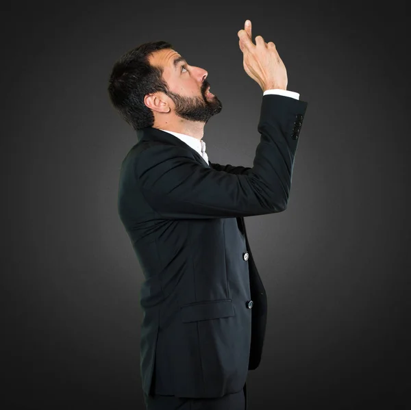 Hombre de negocios guapo con sus dedos cruzando sobre fondo negro —  Fotos de Stock