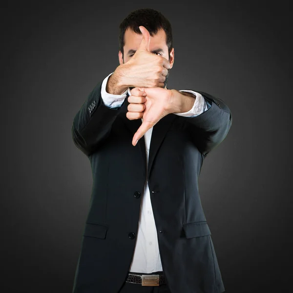 Handsome businessman making good-bad sign on black background