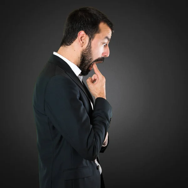 Schöner Geschäftsmann macht Erbrechen Geste auf schwarzem Hintergrund — Stockfoto