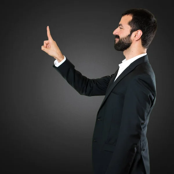 Guapo hombre de negocios tocando en pantalla transparente en negro bac — Foto de Stock