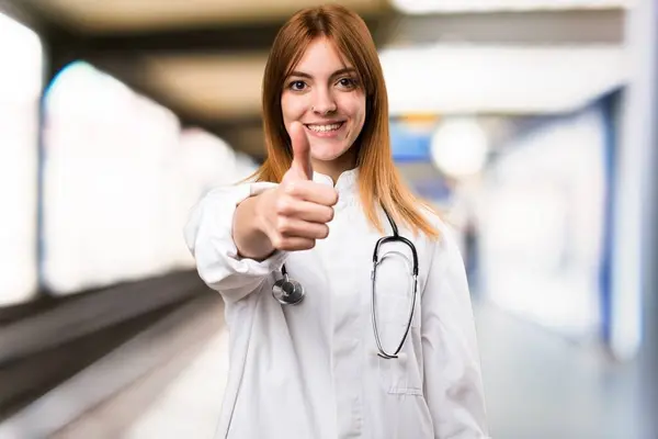 Jonge dokter vrouw met duim omhoog in het ziekenhuis — Stockfoto