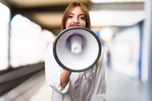 Young doctor woman holding a megaphone in the hospital