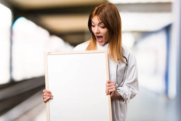 Young doctor woman holding an empty placard in the hospital — Stock Photo, Image