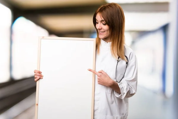 Young doctor woman holding an empty placard in the hospital — Stock Photo, Image