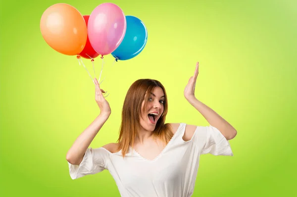 Schönes junges Mädchen hält einen Luftballon und macht Überraschungsgesten — Stockfoto
