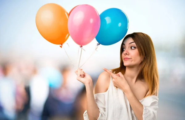 Hermosa joven sosteniendo un globo y señalando a la más tarde — Foto de Stock