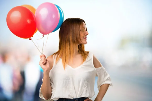 Menina bonita segurando um balão e olhando lateral em un — Fotografia de Stock