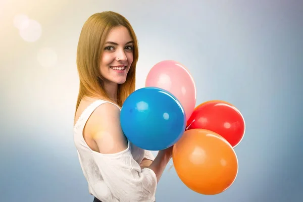 Glücklich schöne junge Mädchen hält einen Luftballon auf unkonzentrierten Backgr — Stockfoto