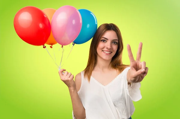 Hermosa joven sosteniendo un globo y contando dos en unfoc — Foto de Stock