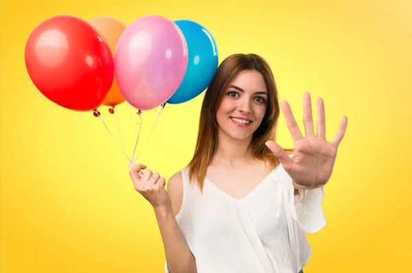 Hermosa joven sosteniendo un globo y contando cinco en unfo — Foto de Stock