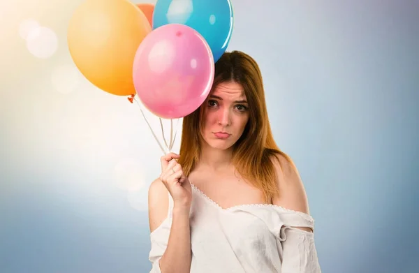 Triste joven hermosa sosteniendo un globo y en la espalda desenfocada — Foto de Stock