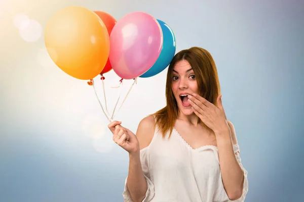 Hermosa joven sosteniendo un globo y haciendo un gesto sorpresa — Foto de Stock
