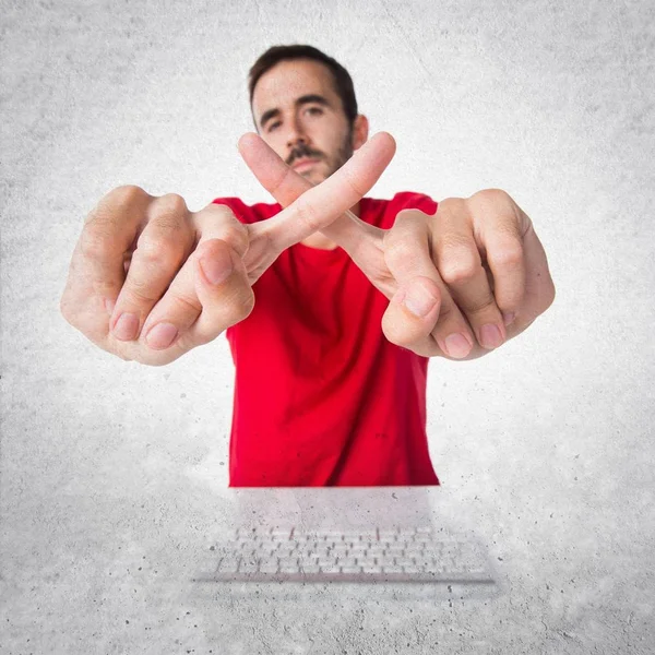 Комп'ютерний технік, який працює зі своєю клавіатурою, робить жест NO — стокове фото