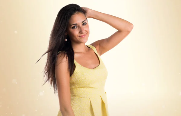 Hübsches Mädchen mit gelbem Kleid auf ockerfarbenem Hintergrund — Stockfoto