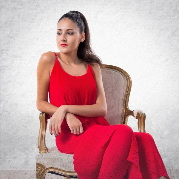 Hezká dívka s červenými šaty na vintage křeslo — Stock fotografie