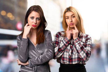 İki arkadaş odaklanmamış arka plan üzerinde üzgün