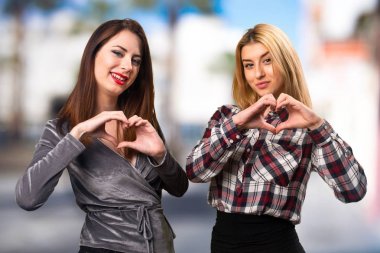 İki arkadaş kendi elleriyle bir kalp üzerinde odaklanmamış arka plan yapma