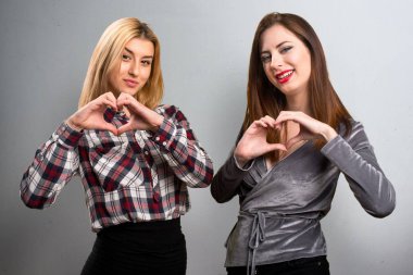 İki arkadaş kendi elleriyle bir kalp üzerinde dokulu arka plan yapma