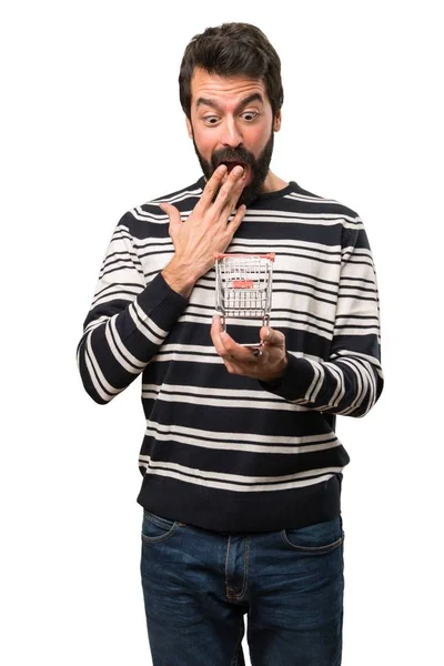 Uomo sorpreso con la barba che tiene un giocattolo del carrello del supermercato — Foto Stock