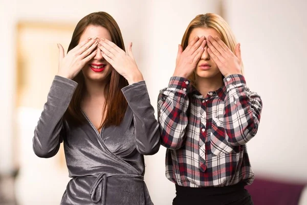 Two friends covering their eyes on unfocused background