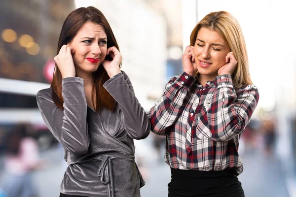 Two friends covering their ears on unfocused background — Stock Photo, Image