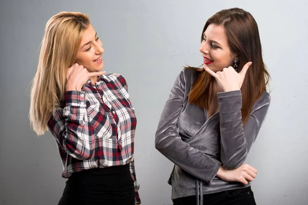 Zwei Freunde machen Handygeste auf strukturiertem Hintergrund — Stockfoto