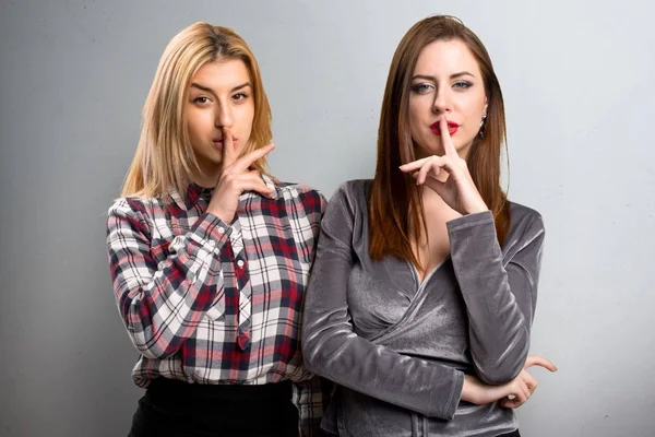 Dos amigos haciendo gesto de silencio sobre fondo texturizado —  Fotos de Stock