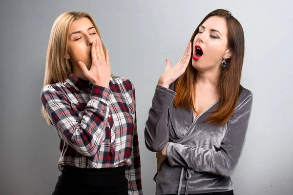 Two friends yawning on textured background — Stock Photo, Image
