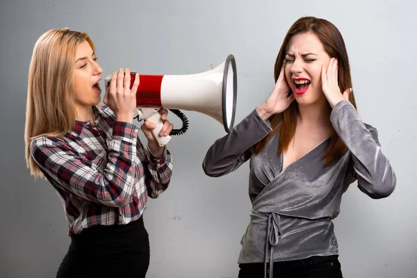 Two friends holding a megaphone on textured background — Stock Photo, Image