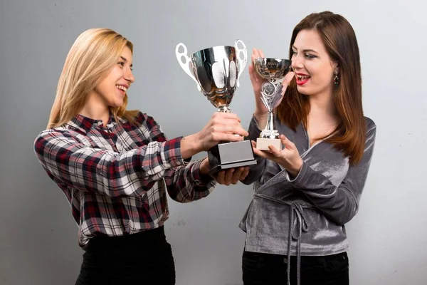 Dois amigos segurando um troféu em fundo texturizado — Fotografia de Stock