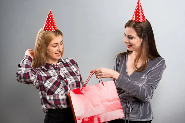 Two friends holding a gift on textured background — Stock Photo, Image