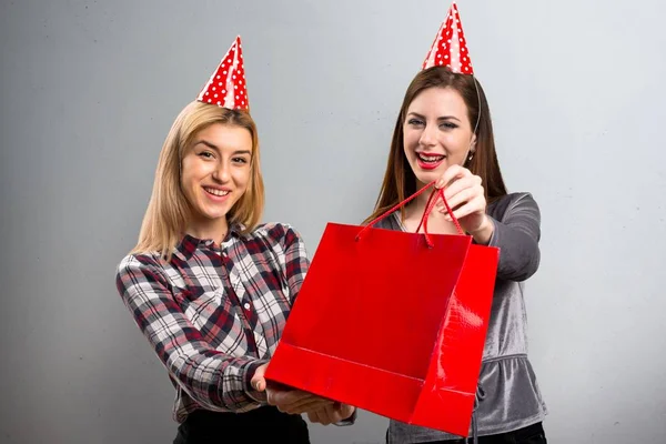 Two friends holding a gift on textured background — Stock Photo, Image