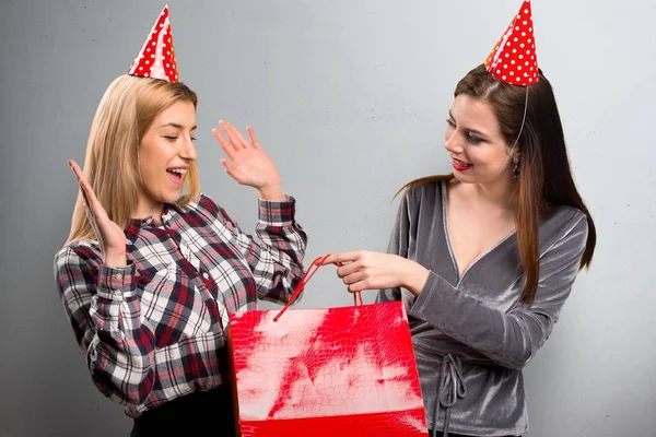 Dos amigos sosteniendo un regalo sobre fondo texturizado —  Fotos de Stock