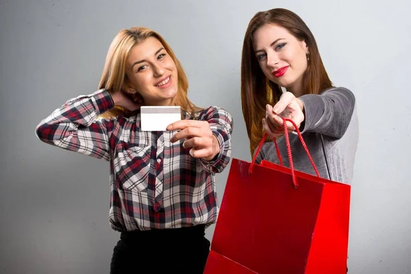 Dois amigos com saco de compras e cartão de crédito em fundo texturizado — Fotografia de Stock