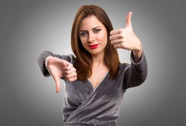 Güzel genç kız iyi-kötü işareti üzerinde dokulu arka plan yapma