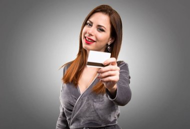 Dokulu arka plan üzerinde bir kredi kartı tutan güzel genç kız