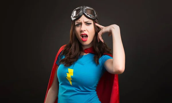 Bastante chica superhéroe haciendo gesto loco sobre fondo negro —  Fotos de Stock