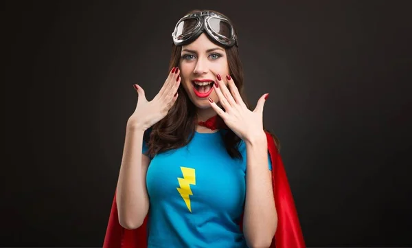 Mooie superheld meisje maken verrassing gebaar op zwarte achtergrond — Stockfoto