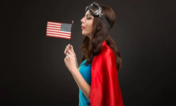 黒の背景にアメリカの国旗を保持しているかなりのスーパー ヒーロー少女 — ストック写真