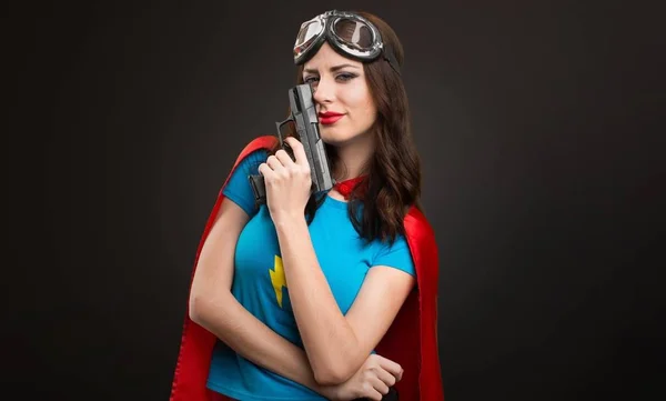 Bastante chica superhéroe sosteniendo una pistola sobre fondo negro — Foto de Stock