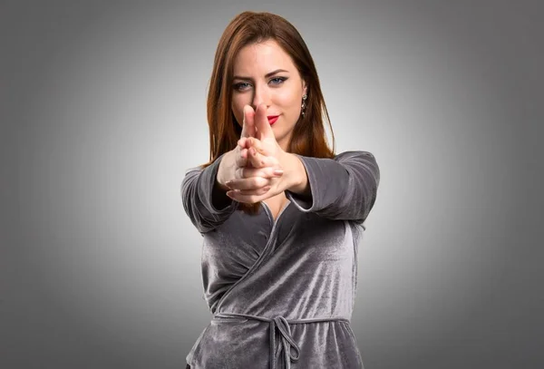 Vacker ung flicka gör pistol gest på texturerat bakgrund — Stockfoto