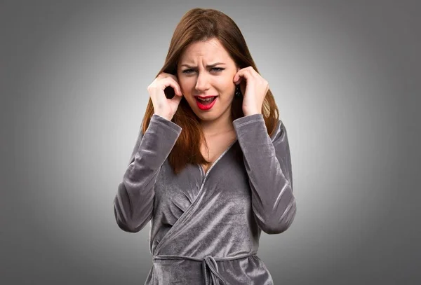 Schönes junges Mädchen, das ihre Ohren auf strukturiertem Hintergrund bedeckt — Stockfoto