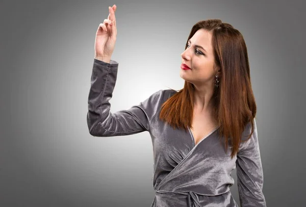 Schönes junges Mädchen mit Daumendrücken auf strukturiertem Hintergrund — Stockfoto