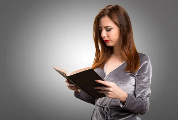 Красива молода дівчина читає книгу на фактурному фоні — стокове фото
