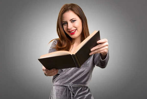 Beautiful young girl reading book on textured background — Stock Photo, Image