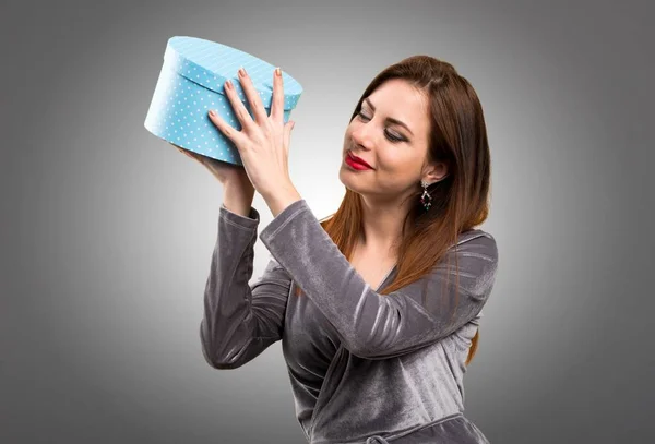 Beautiful young girl holding a gift on textured background — Stock Photo, Image