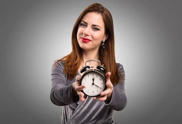 Beautiful young girl holding vintage clock on textured background — Stock Photo, Image